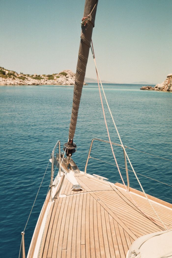 cursos View of sailboat deck cruising through clear blue waters on a sunny summer day.